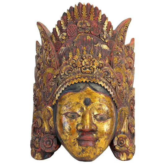 Detaillierte Vorderansicht der handgeschnitzten balinesischen Tanzmaske von Dewi Sinta, die die heiteren Gesichtszüge und die kunstvoll gestaltete, mehrschichtige Krone zeigt.