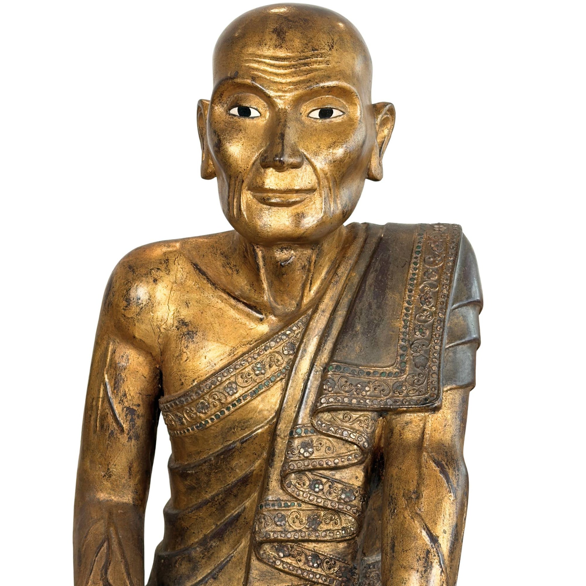 Gesicht der burmesischen Holzstatue des Hauptschülers Sariputta mit handgeschnitzten Falten und verwittertem Blattgold.