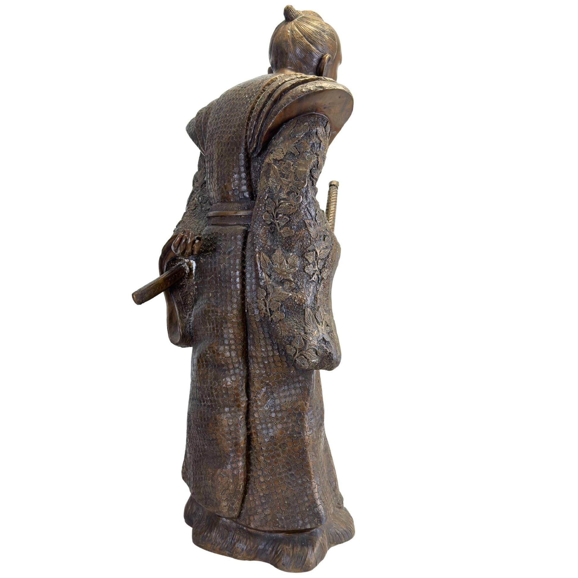 Schräge Rückseite der bronzenen Meiji-Statue, die das florale Hochrelief an den Ärmeln und die fließenden Falten zeigt.