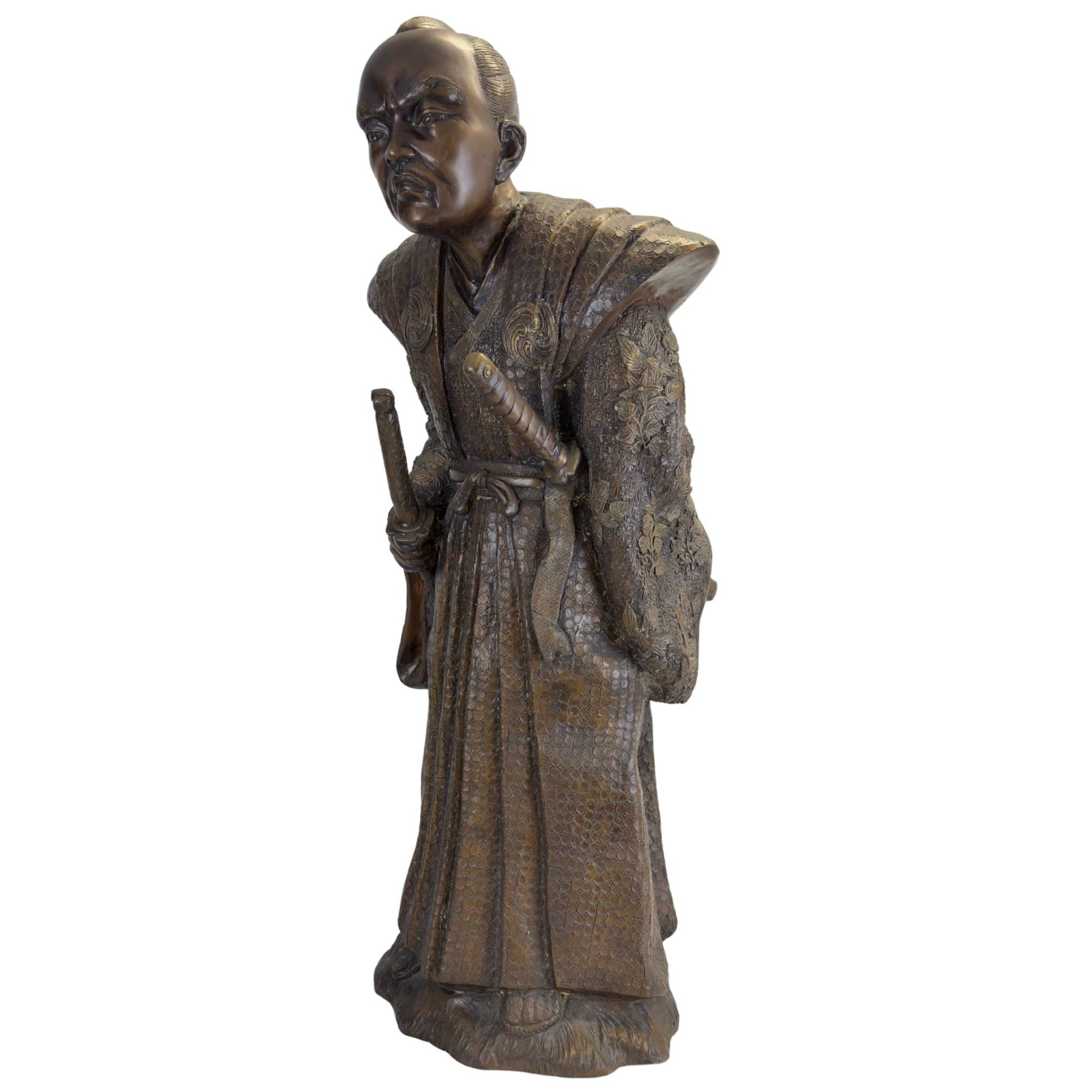 Dreiviertel-Frontalansicht des bronzenen Samurai in seiner zeremoniellen Kriegshaltung, wobei die Daisho-Schwerter deutlich sichtbar sind.