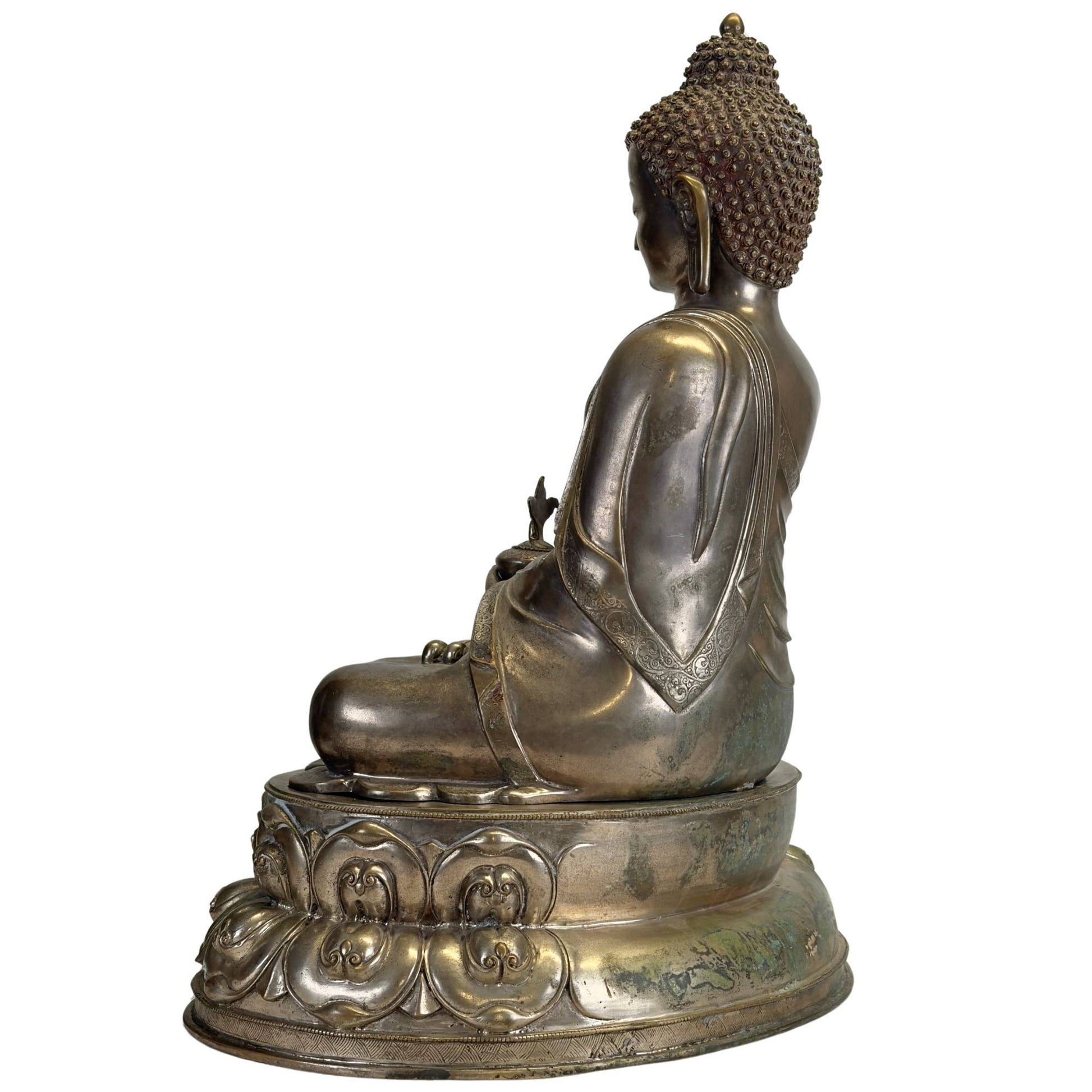 Linke Seite eines antiken Newar Bhaisajyaguru aus versilberter Bronze auf einem zweiteiligen Lotusthron, mit natürlicher Patina, gravierter Mönchsrobe und altersbedingten Gebrauchsspuren.